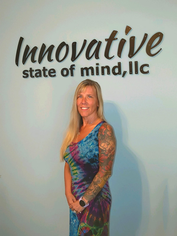 Theresa Huffines standing under sign that says Innovative State of Mind LLC